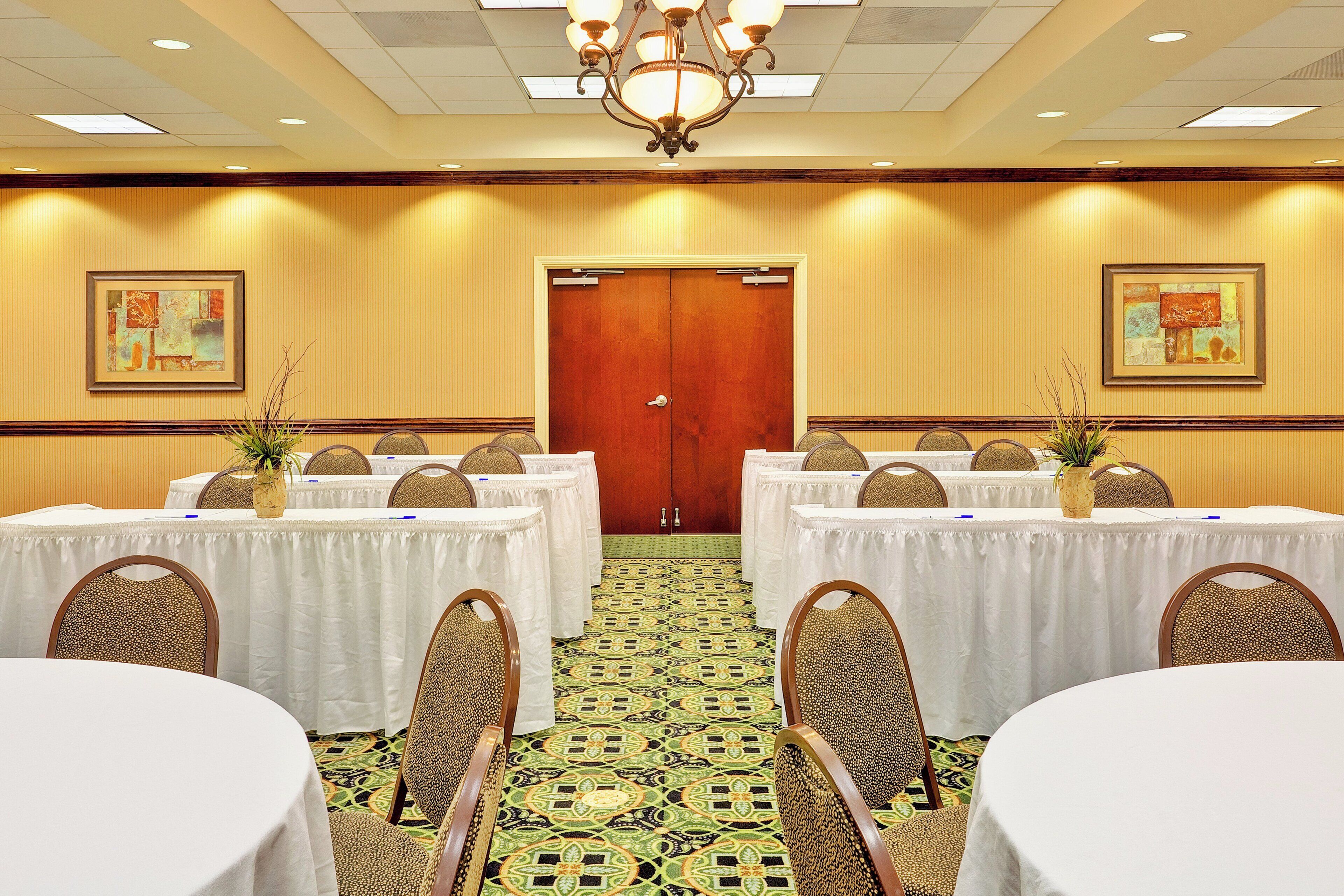 A conference room with tables and chairs, a patterned carpet, and artwork on the walls.