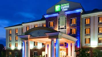Welcome to Holiday Inn Express & Suites, featuring a covered entrance with white columns and a warm, inviting atmosphere.