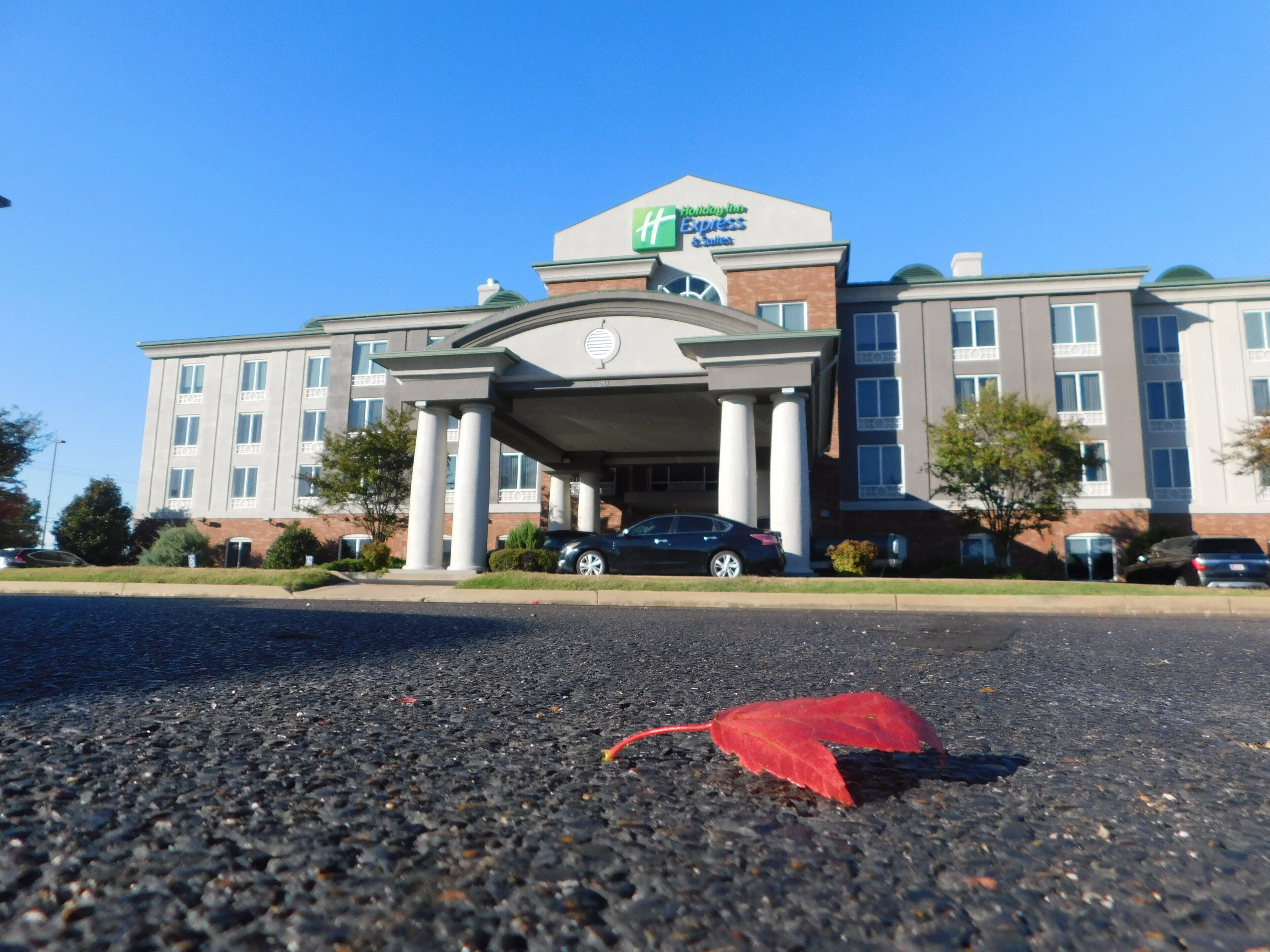 A Holiday Inn Express building with a covered entrance, multiple windows, and parked cars.