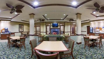 A hotel lobby with a central seating area, a fireplace, and a television mounted on the wall.