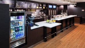 Eine moderne Hotelbar mit einem Getränkekühler, einer Kaffeemaschine und einer Obstauslage.