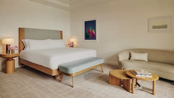 A hotel room with a large bed, a bench, a sofa, and a small table with books.