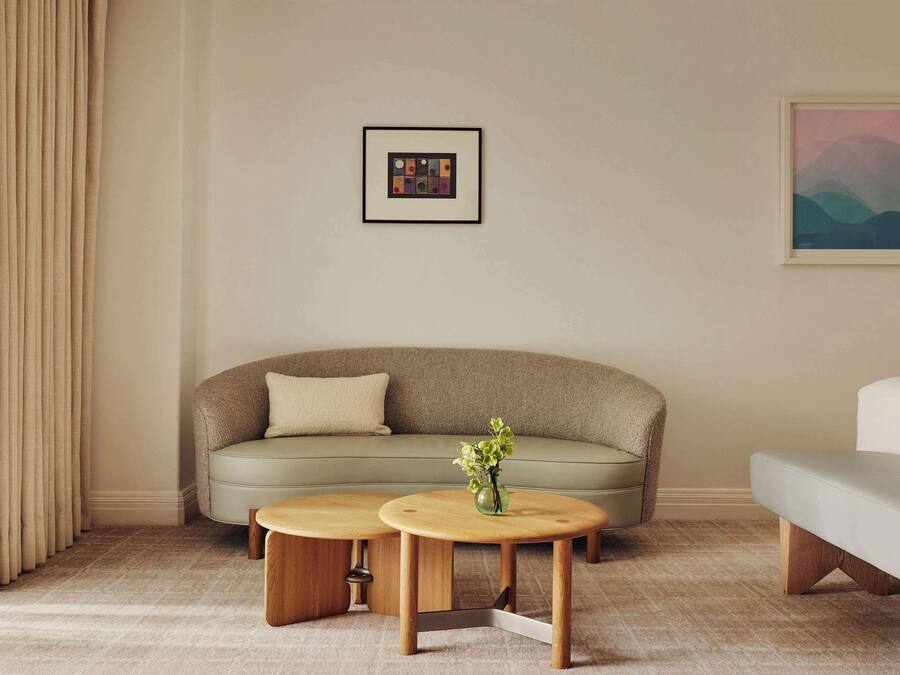 A modern living room with a beige sofa, two wooden side tables, a framed picture, and a painting on the wall.