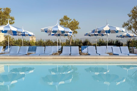 Una piscina al aire libre, camas de piscina con cargo, sombrillas