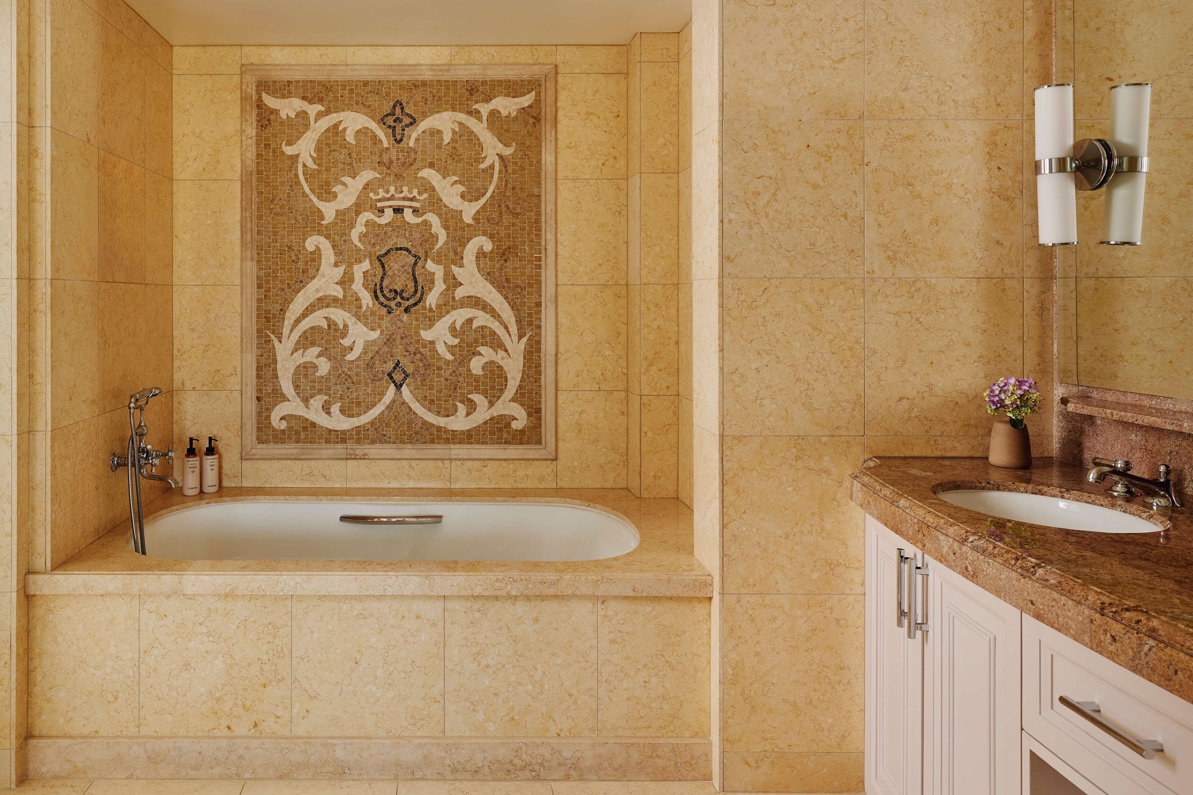 Une salle de bain avec une baignoire sur pieds, un lavabo et un mur décoré de carreaux.