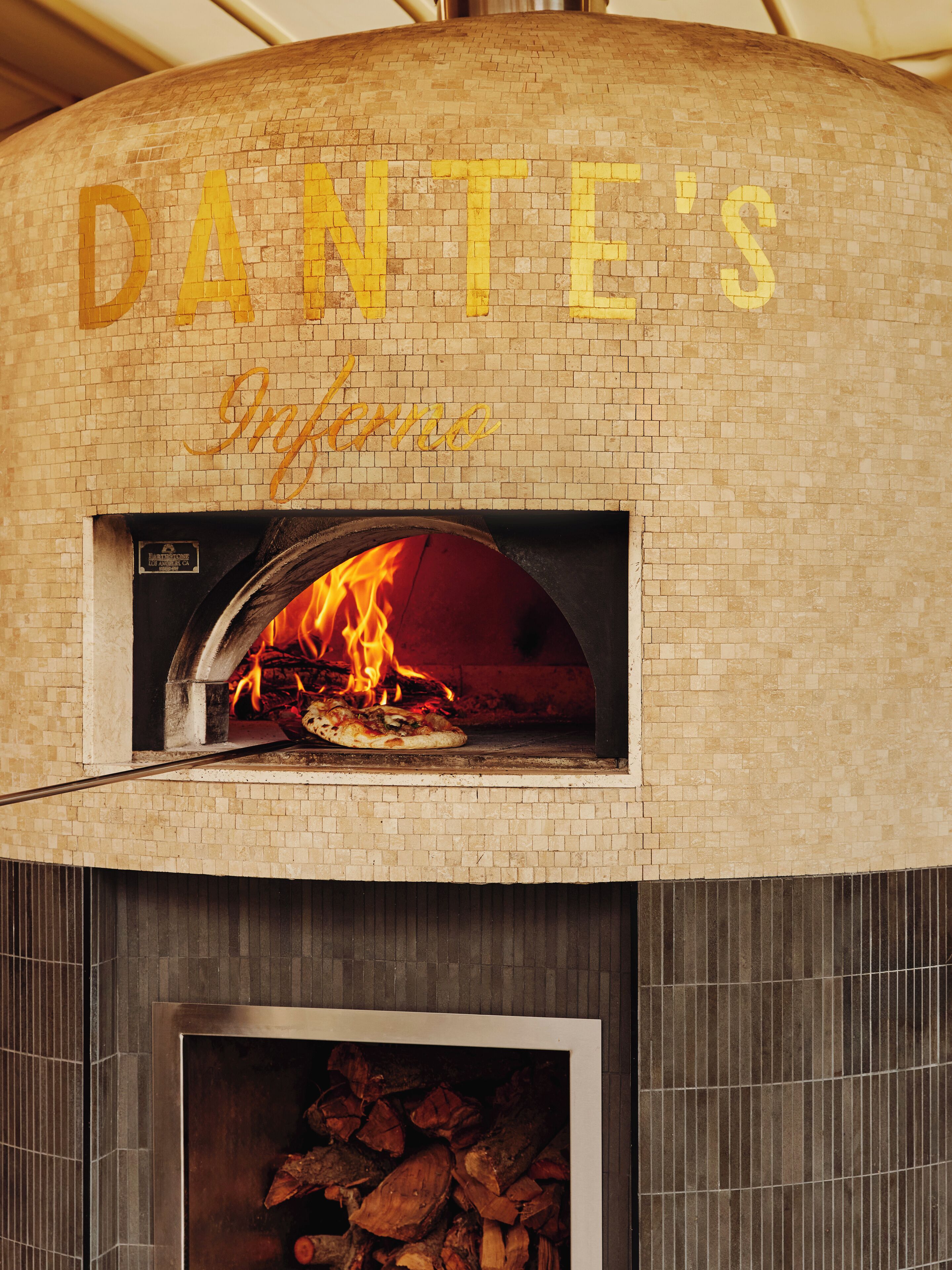 A brick oven pizza oven with a sign above it reading "DANTE'S Infamous."