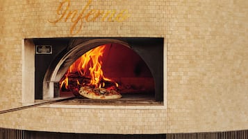 A brick oven pizza oven with a sign above it reading "DANTE'S Infamous."