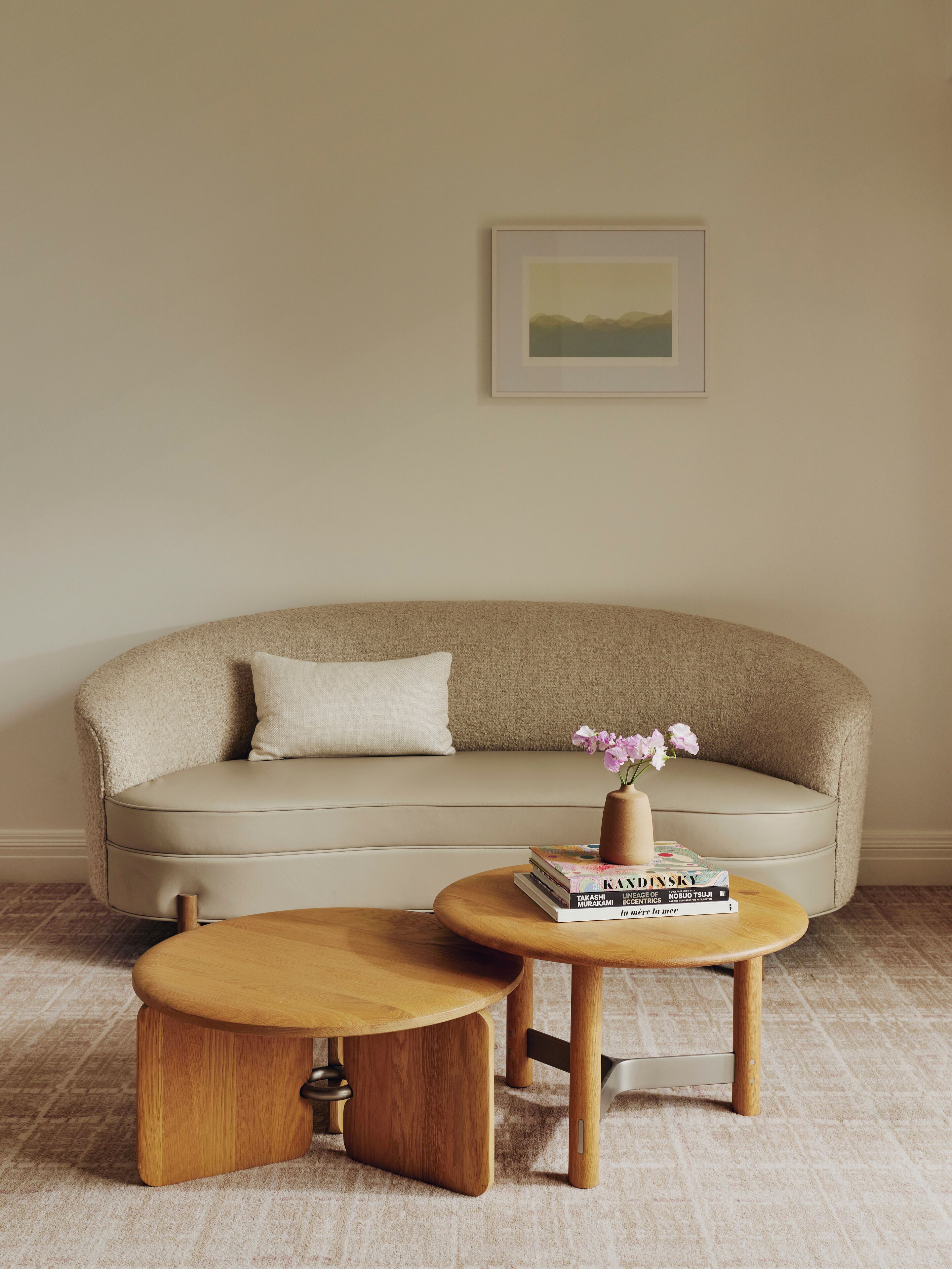 A living room with a beige sofa, a small wooden coffee table, and a framed picture on the wall.