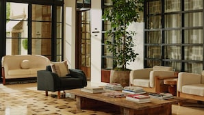A spacious living area with a large window, a potted plant, and a coffee table with books.