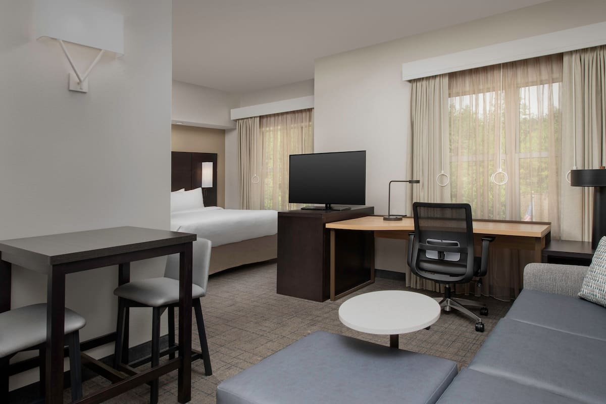 Une chambre d’hôtel avec un lit, un bureau, une télévision, un canapé et une petite table.
