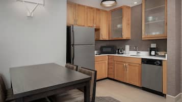 A modern kitchen with wooden cabinets, a stainless steel refrigerator, a microwave, and a dishwasher.