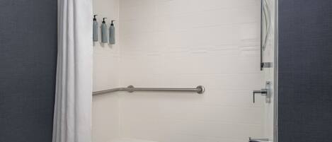 A bathroom with a bathtub, a shower, and a grab bar.