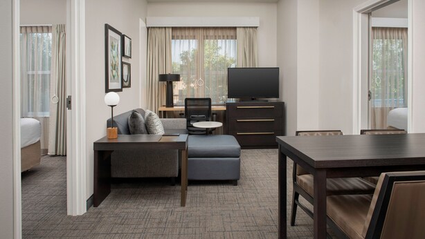 A hotel room with a bed, a sofa, a desk with a chair, a television, and a dining table. - Residence Inn by Marriott Birmingham/Hoover (Birmingham)