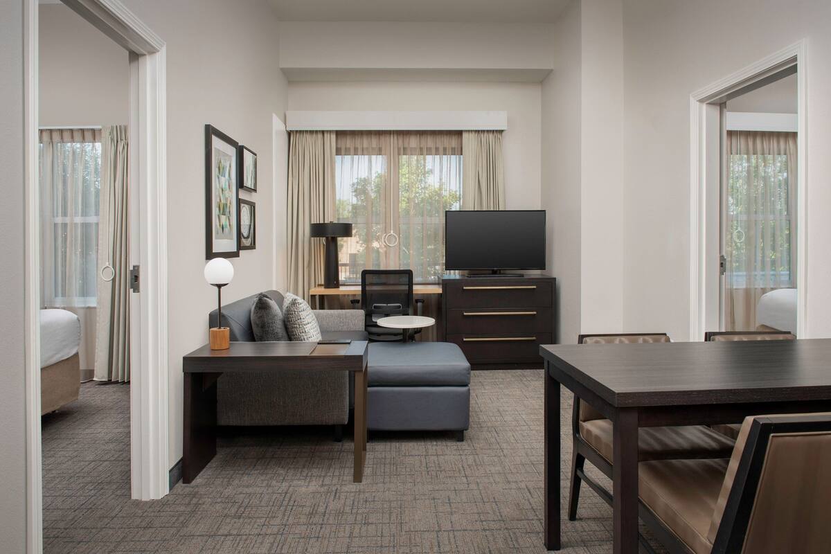 Une chambre d’hôtel comprenant un lit, un canapé, un bureau avec une chaise, une télévision et une table à manger.