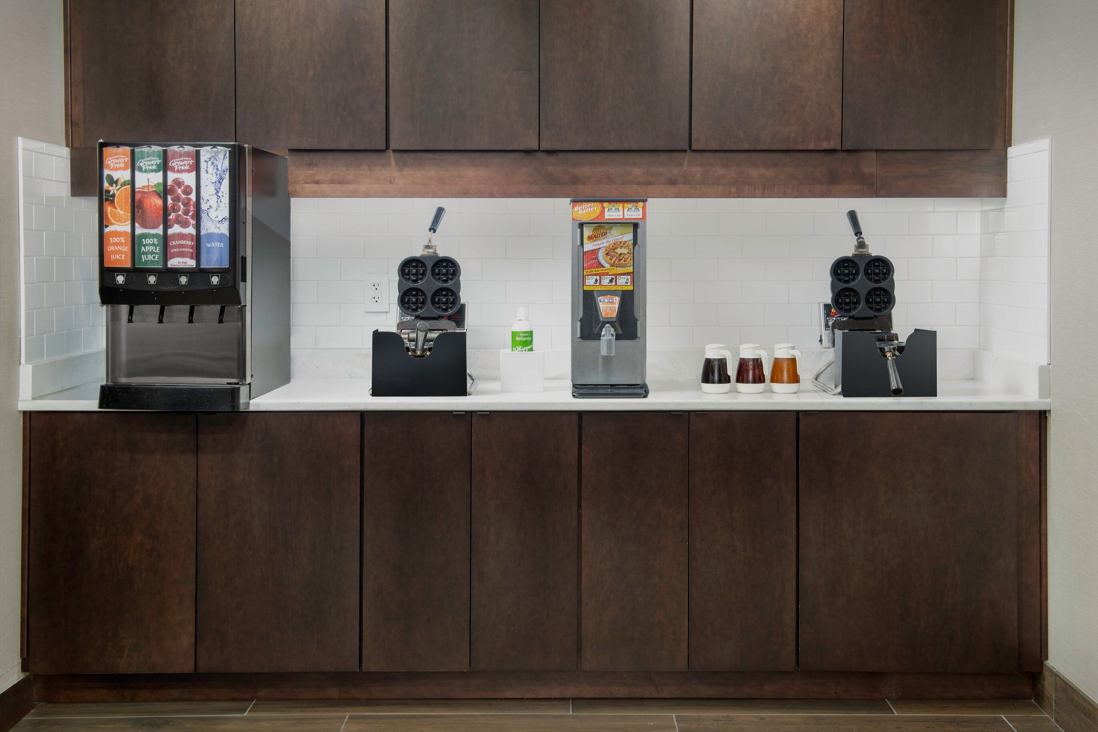 A kitchen area with a coffee machine, a water dispenser, and a food display.