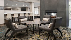 A modern lounge area with a round table surrounded by four grey upholstered chairs, a patterned carpet, and a fireplace. - Residence Inn by Marriott Birmingham/Hoover (Birmingham)