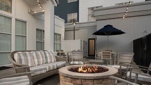 An outdoor patio area with a stone fire pit, wicker furniture, and a large umbrella. - Residence Inn by Marriott Birmingham/Hoover (Birmingham)