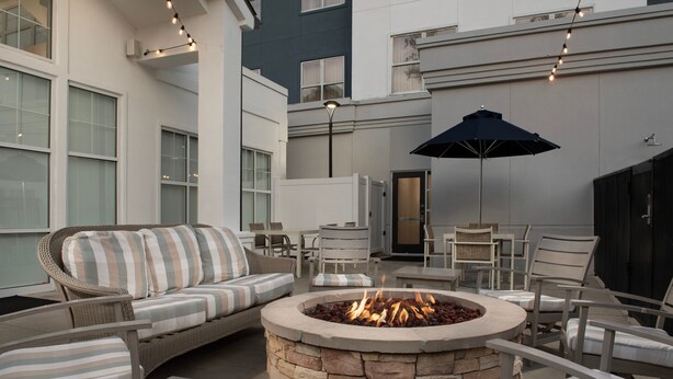 An outdoor patio area with a stone fire pit, wicker furniture, and a large umbrella. - Residence Inn by Marriott Birmingham/Hoover (Birmingham)