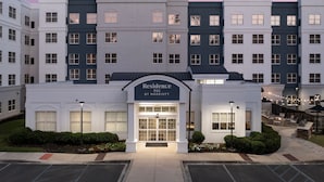 A multi-story hotel with a central entrance, multiple windows, and a landscaped outdoor area with seating. - Residence Inn by Marriott Birmingham/Hoover (Birmingham)