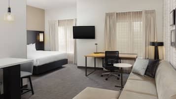 Una habitación de hotel con cama, escritorio, silla, sofá y televisor.