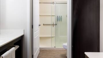 Une salle de bain avec une douche à parois de verre, des toilettes et un lavabo, avec une serviette suspendue à un porte-serviettes.