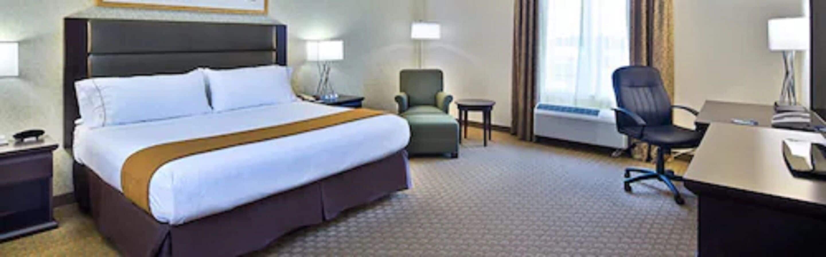 Una habitación de hotel con una cama grande, un escritorio, una silla y una mesita.