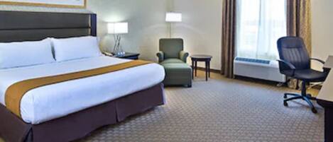 A hotel room with a large bed, a desk, a chair, and a small table.