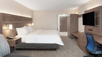 A hotel room with a bed, bedside tables, a desk with a chair, a television, and a wardrobe.