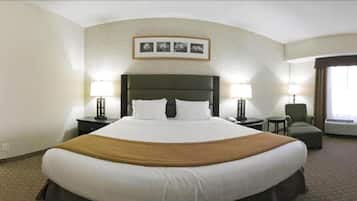 A hotel room with a large bed, two bedside tables with lamps, a chair, and a framed picture on the wall.