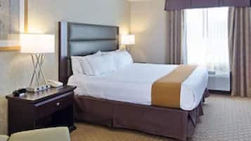 Een hotelkamer met een bed, nachtkastje, lamp, stoel en een open haard.