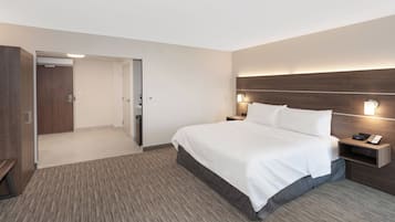 Habitación de hotel con una cama grande, una mesita de noche con teléfono, y una puerta que da al baño.