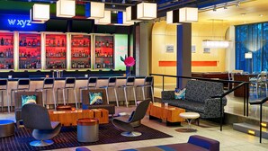 A bar area with a neon sign, seating arrangements, and a wine cooler. - Aloft by Marriott Chicago O'Hare (Rosemont)