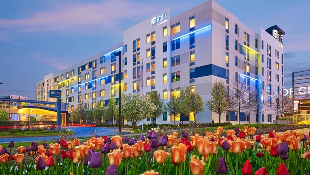 A modern hotel with a flat roof, multiple floors, and a well-lit facade. - Aloft by Marriott Chicago O'Hare (Rosemont)