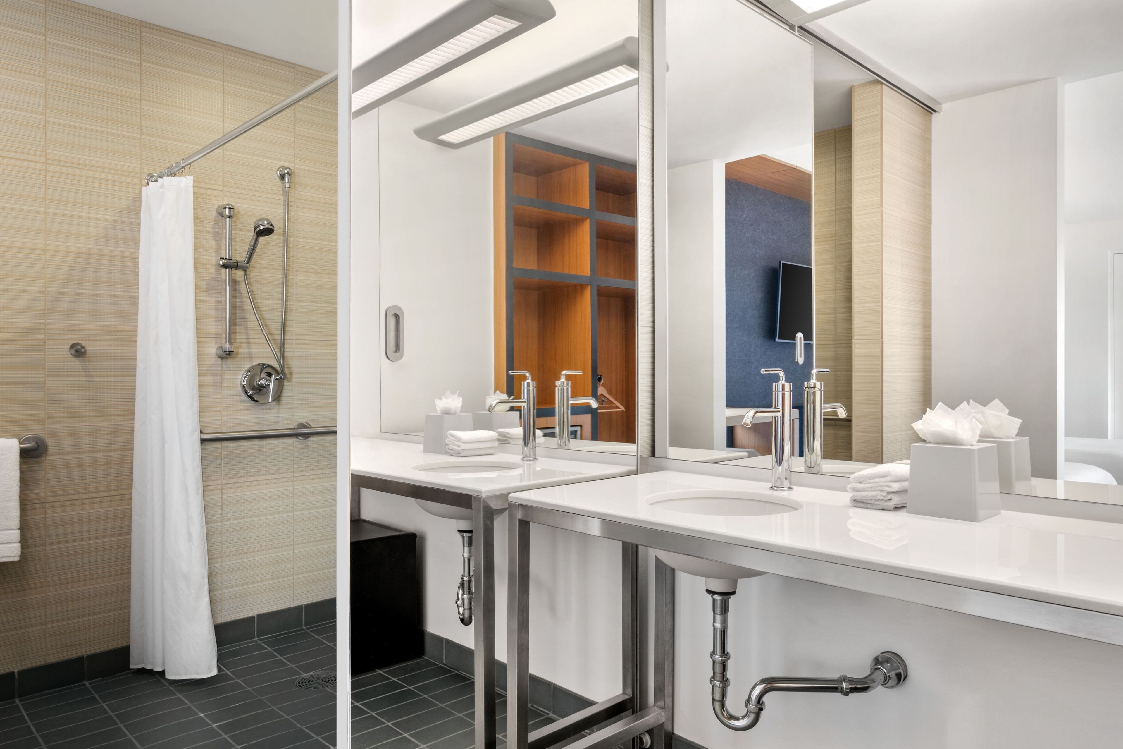 A modern bathroom with a shower, two sinks, a mirror, and a towel rack.