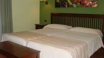 Una cama doble con cubrecama a rayas, una mesita de noche de madera, una mesa y una lámpara de pared.