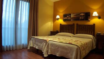Una habitación de hotel con una cama, dos mesitas de noche, una lámpara, un cuadro en la pared y una ventana con cortinas.