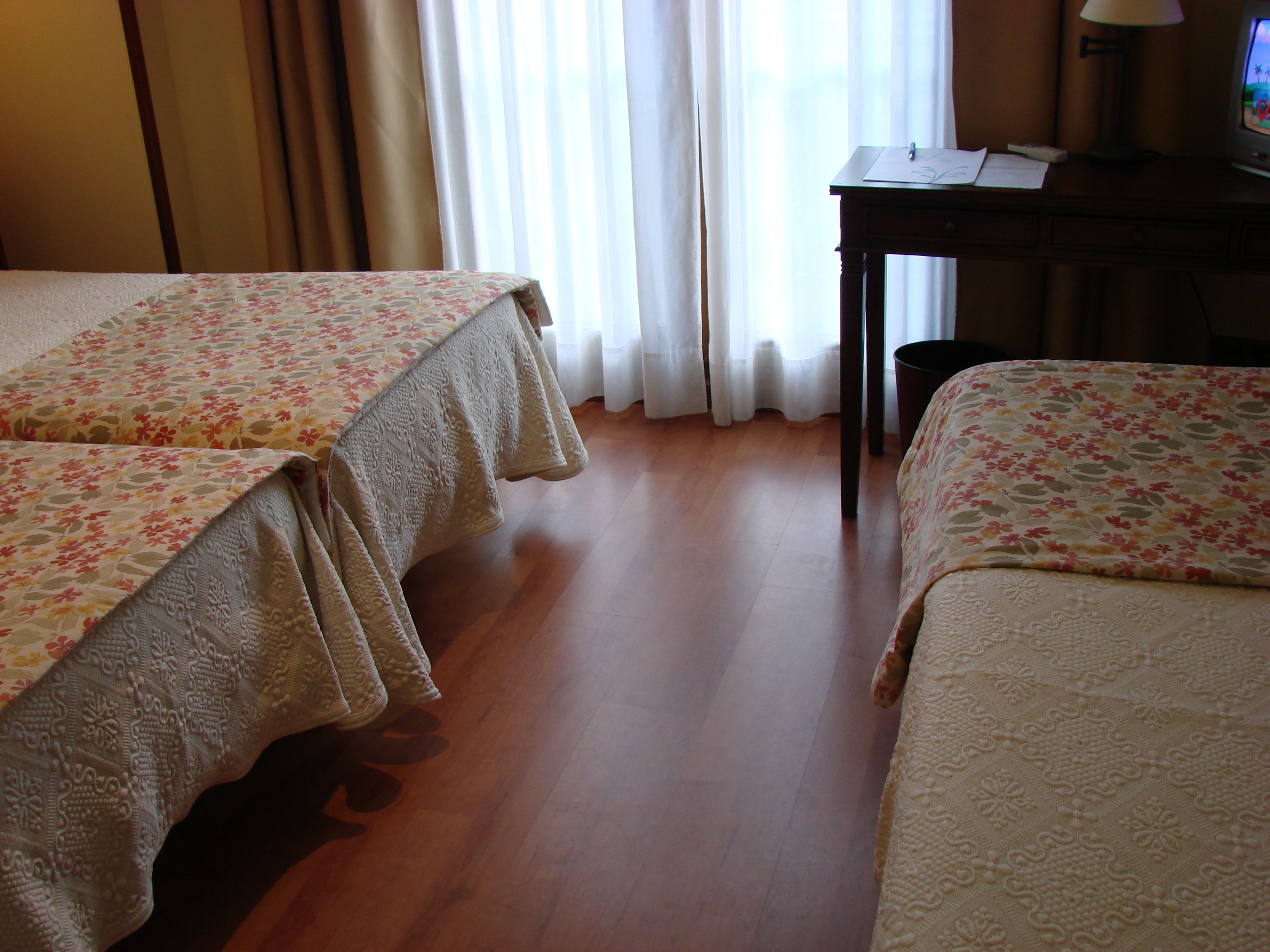 Een hotelkamer met twee bedden, een bureau met lamp en een televisie.