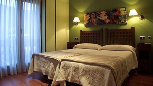 Una cama doble con cabecera de madera, dos mesitas de noche y una obra de arte floral sobre la cama.