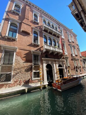 A historic building with a canal in front, featuring a boat docked at the entrance.