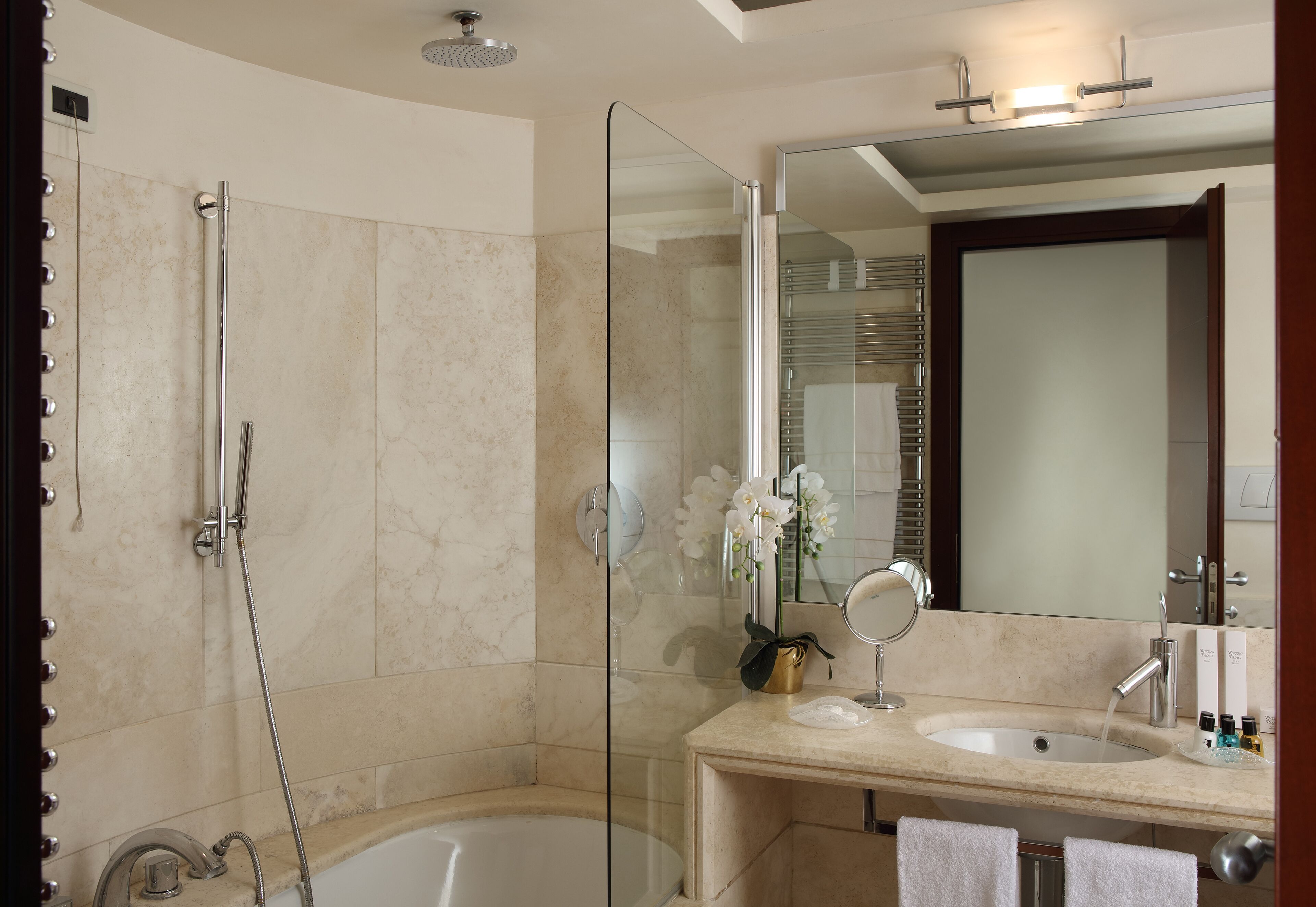 A modern bathroom with a glass shower enclosure, a bathtub, a vanity with a sink, and a large mirror.