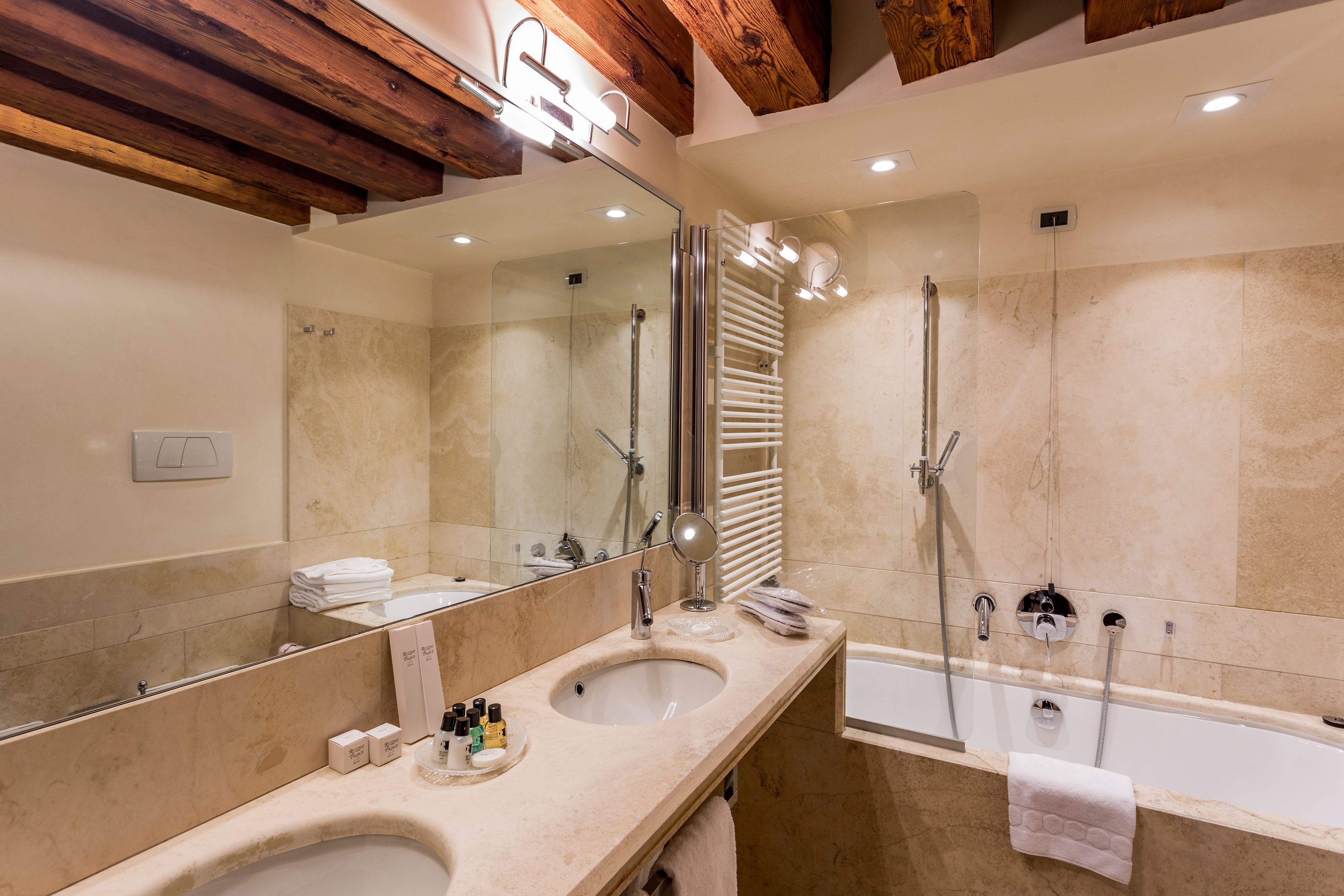 A modern bathroom with two sinks, a large mirror, a glass-enclosed shower, and a bathtub.
