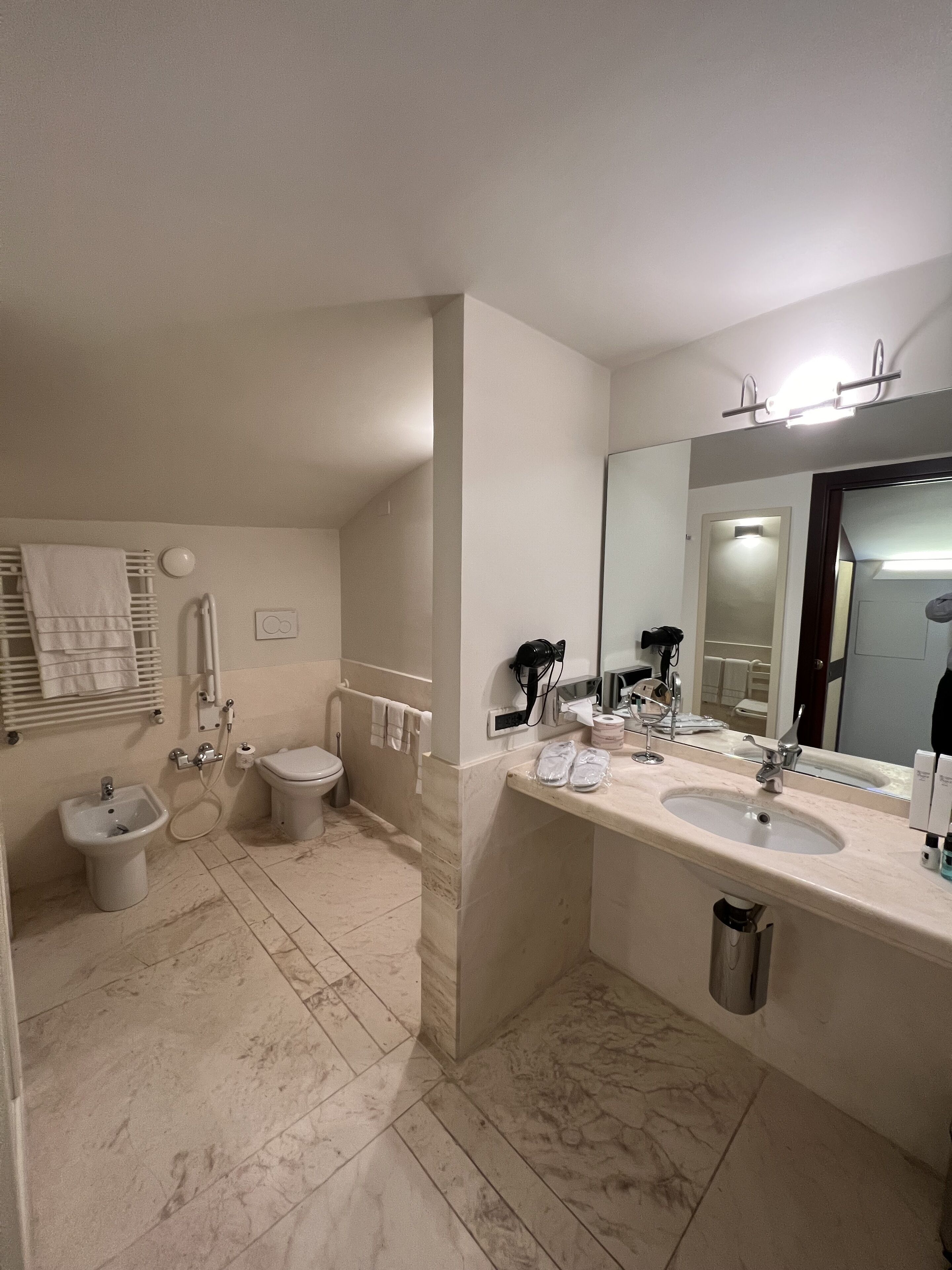 A modern bathroom with a bidet, toilet, and a large mirror.