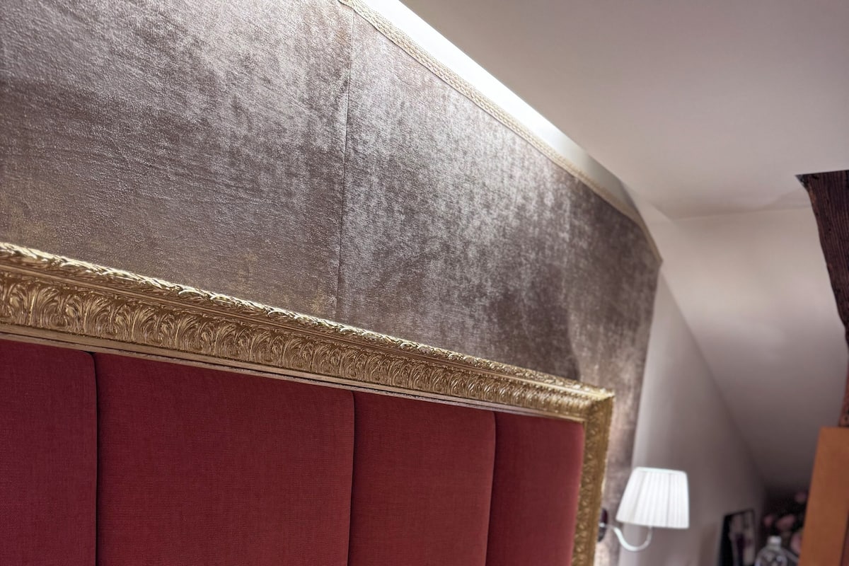 A hotel room with a red upholstered headboard, white bedding, and a lamp on a bedside table.