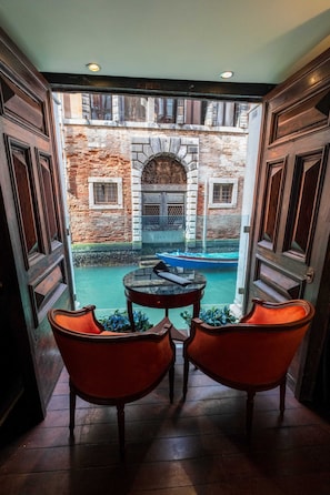 A room with a view of a canal, a table, and two chairs.