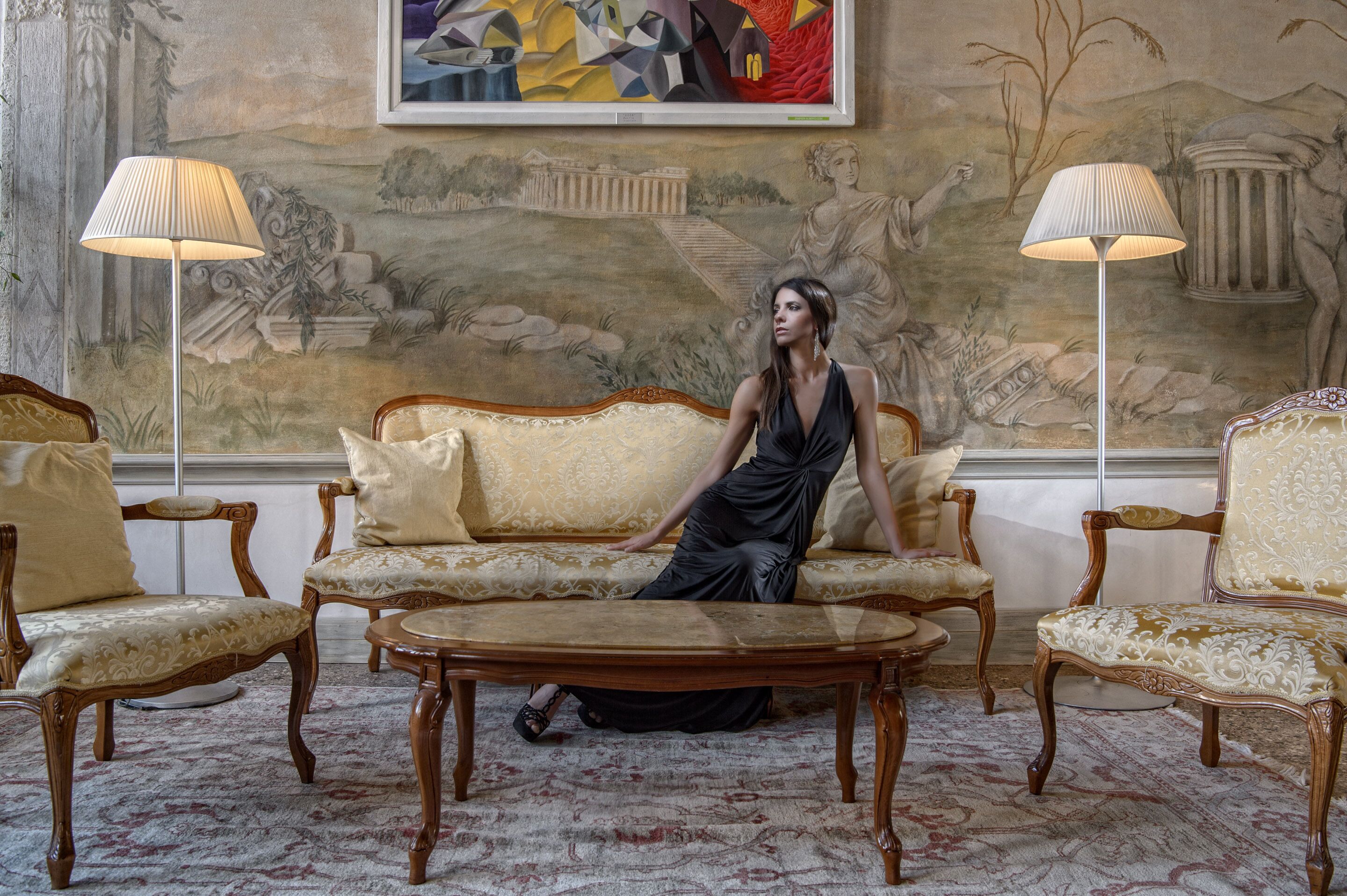 A room with a sofa, two armchairs, a coffee table, and two floor lamps.