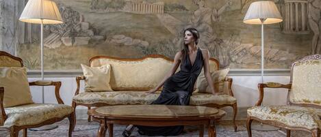 A room with a sofa, two armchairs, a coffee table, and two floor lamps.