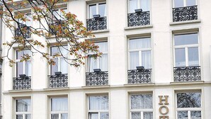 A hotel with a sign reading "HOTEL" and "le Rubens" on the ground floor. There are outdoor seating areas with tables and chairs. - Hotel The Moon (Brussels)
