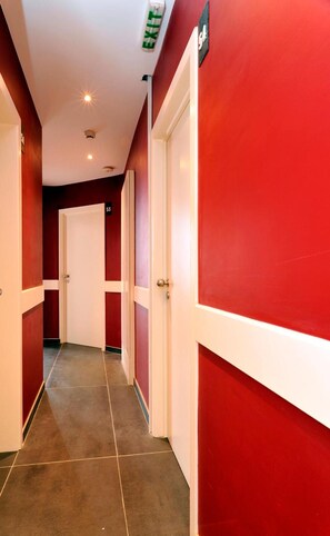 A hallway with red walls, white doors, and a tiled floor. - Hotel The Moon (Brussels)