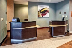 A reception area with two dark wooden reception desks, a digital kiosk, and a large abstract painting on the wall. - Courtyard by Marriott Newport News Airport (Newport News)