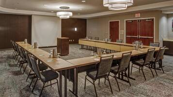 A conference room with a long table, chairs, a podium, and a projector screen.